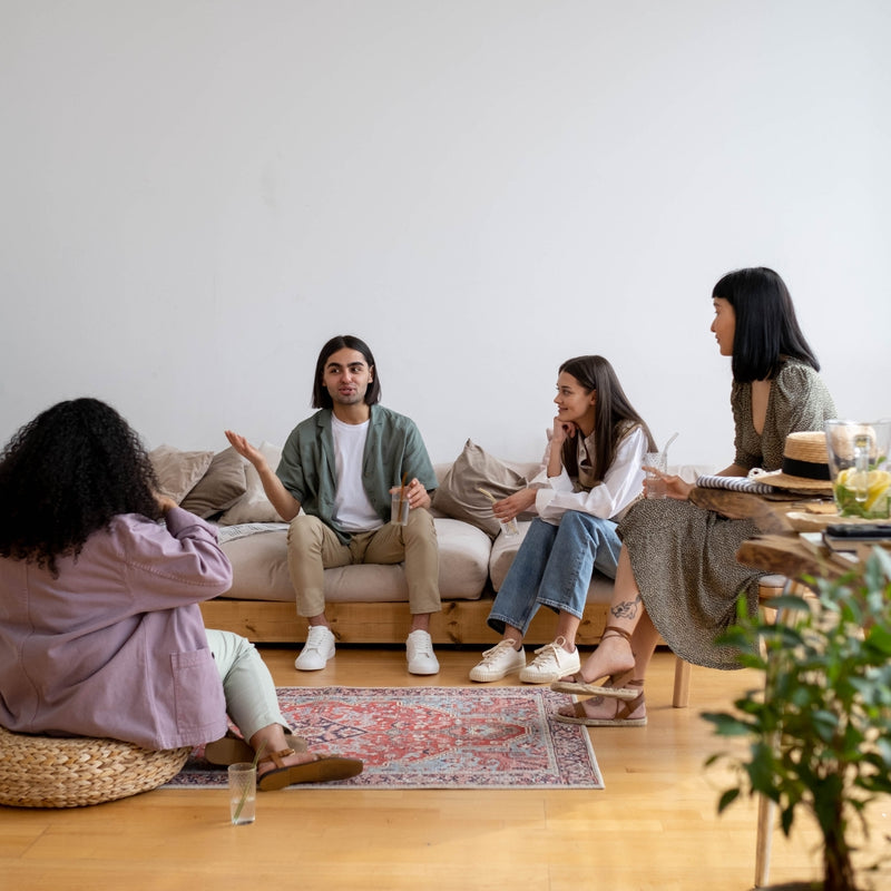 Group of people sitting on a couch and floor in a living room