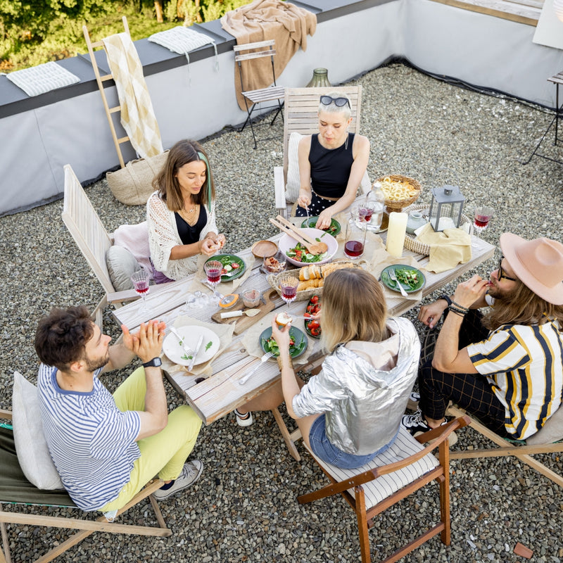 Group of people enjoying a meal together outdoors on a rooftop.